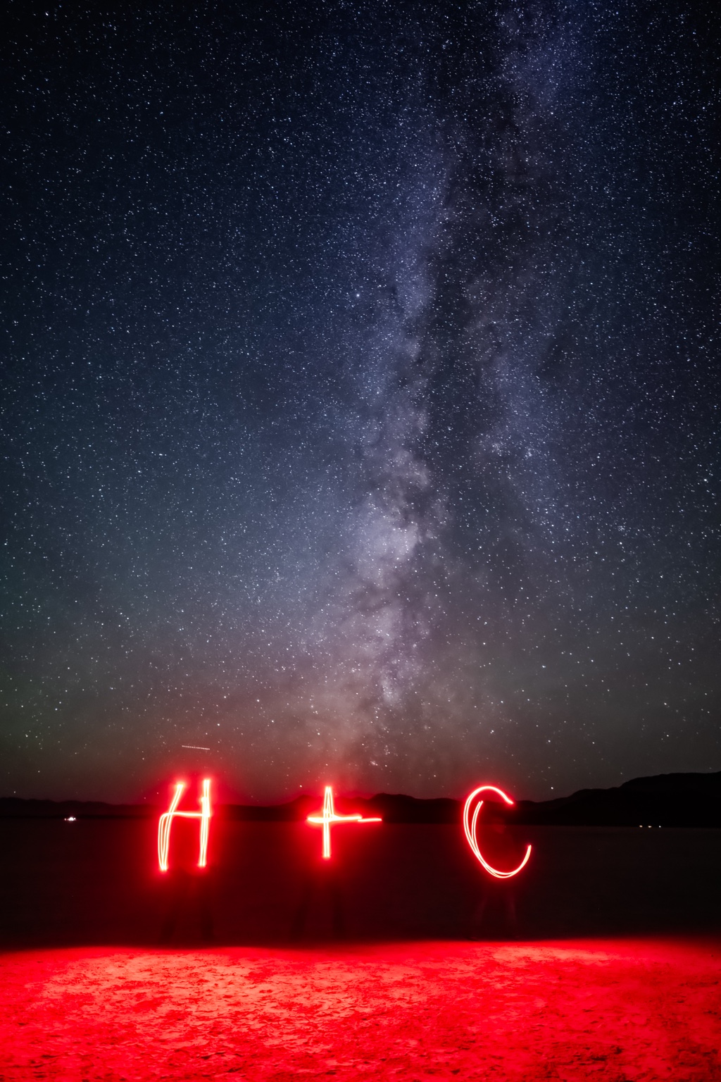 Two red light-painted letters and a circle under the Milky Way