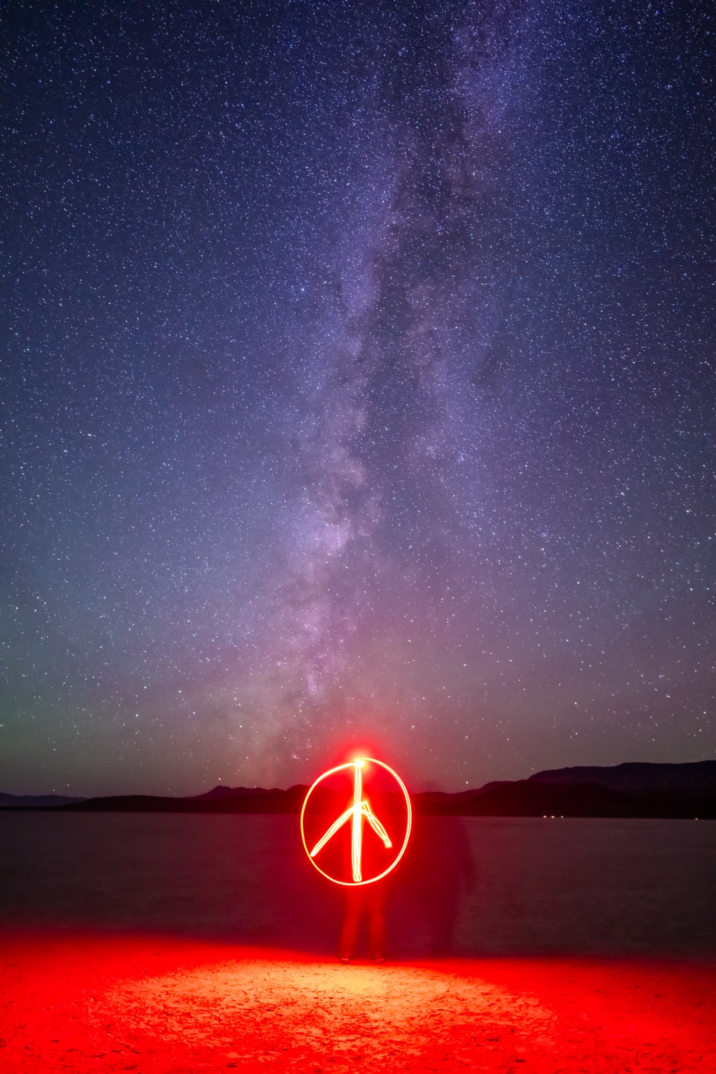 Red light painting beneath a vertical Milky Way