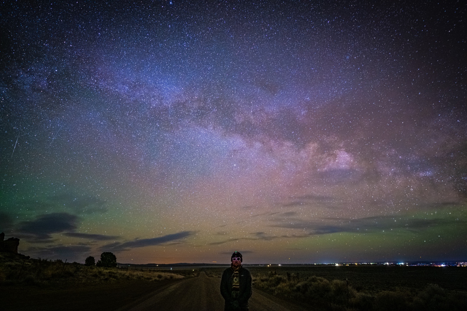 A person on a quiet road beneath a broad Milky Way