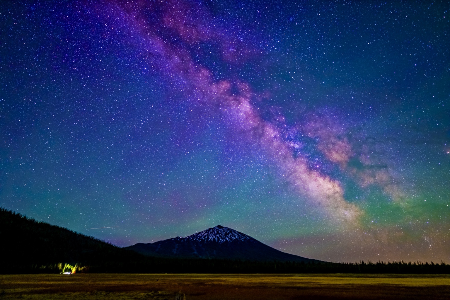 Milky Way arch above a mountain and open field
